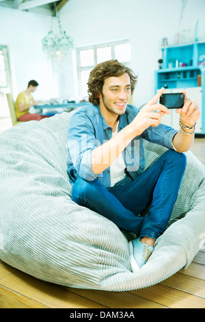 Man using cell phone in beanbag chair Stock Photo
