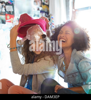 Women playing with hats in bedroom Stock Photo