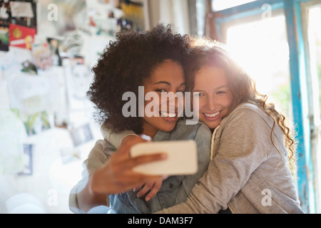 Women taking picture together in bedroom Stock Photo