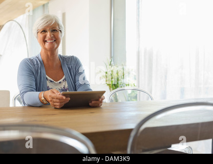 Older woman using tablet computer at table Stock Photo