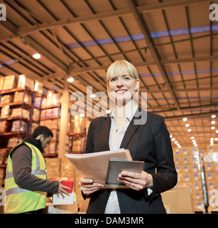 Businesswoman with folder and tablet computer in warehouse Stock Photo