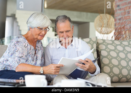 Older couple reading papers together on sofa Stock Photo
