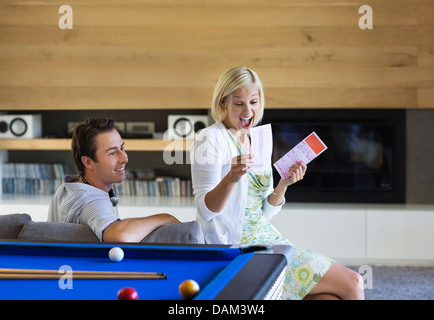 Couple checking lottery tickets on sofa Stock Photo
