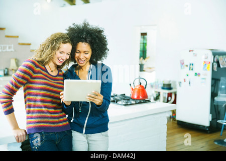 Women using tablet computer in kitchen Stock Photo