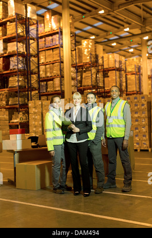 Businesswoman and workers smiling in warehouse Stock Photo