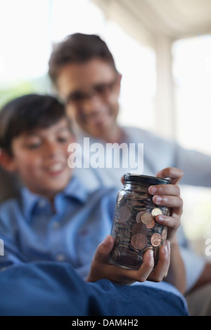 Father and son holding change jar Stock Photo