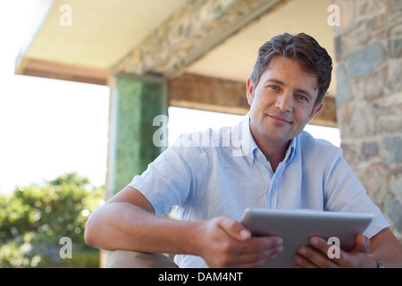 Man using tablet computer on porch Stock Photo