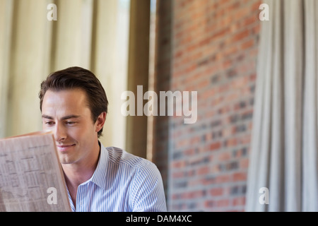 Businessman reading newspaper indoors Stock Photo