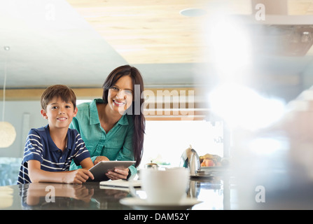 Mother and son using tablet computer in kitchen Stock Photo