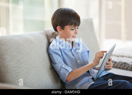 Boy using tablet computer on sofa Stock Photo