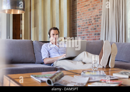 Man using laptop on sofa Stock Photo