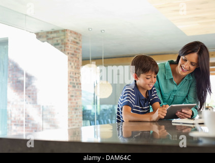 Mother and son using tablet computer in kitchen Stock Photo