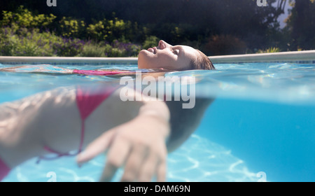 Woman floating in swimming pool Stock Photo