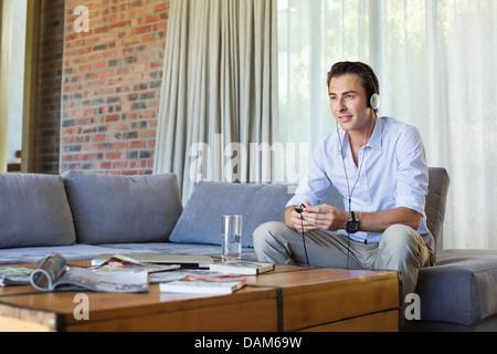 Man listening to headphones on sofa Stock Photo