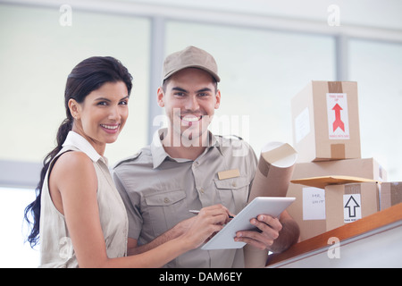 Woman signing for packages from delivery boy Stock Photo