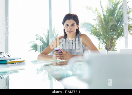 Businesswoman using cell phone in office Stock Photo