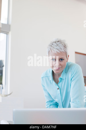Businesswoman standing at desk in office Stock Photo