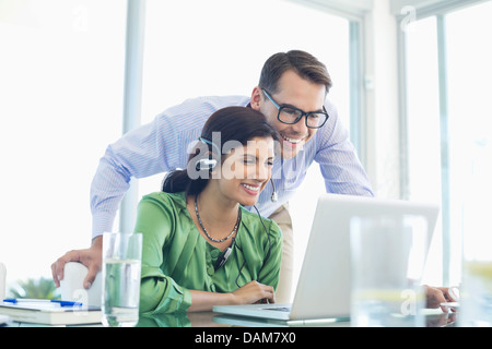 Business people using laptop together at desk Stock Photo