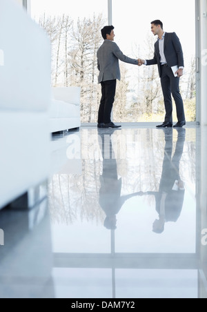Businessmen shaking hands in office Stock Photo