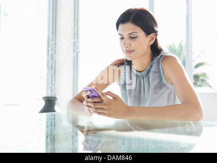 Businesswoman using cell phone at desk Stock Photo