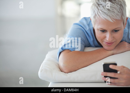 Businesswoman using cell phone on sofa Stock Photo