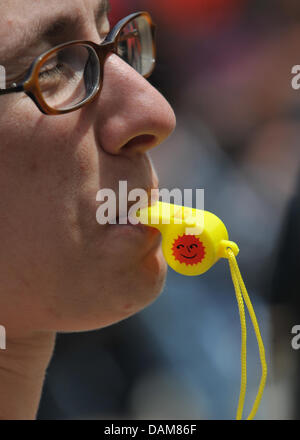 A woman takes part in a demonstration against nuclear power and blows a yellow whistle with a sun on it on Koenigsplatz in Munich, Germany, 28 May 2011. Several thousand people took the streets in Munich to protest against nuclear power and police reports estimate that there were around 11,500 demonstrators in Munich alone. Photo: ANDREAS GEBERT Stock Photo