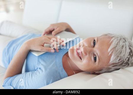 Woman holding tablet computer on sofa