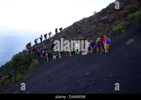 People climbing Stromboli, active volcano in the Aeolian islands, Sicily, Italy. Group of hikers in trekking activity on holidays in Sicilia, Italia Stock Photo