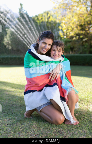 Mother and son wrapped in towel in backyard Stock Photo