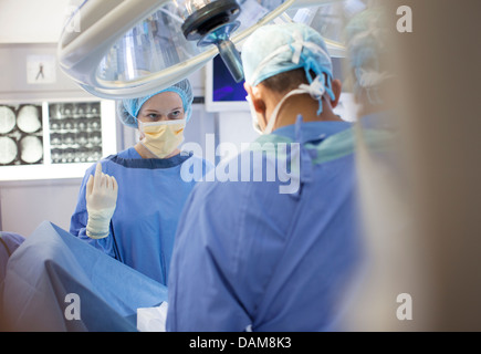 Surgeons standing over patient in operating room Stock Photo