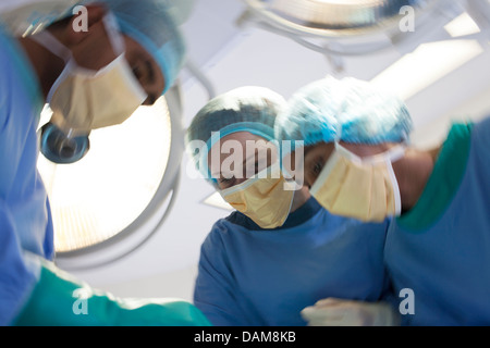 Surgeons bent over patient in operating room Stock Photo