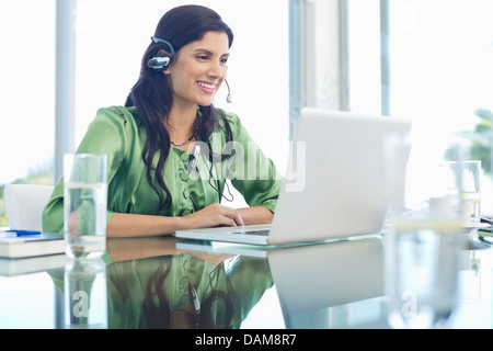 Businesswoman listening to headphones at desk Stock Photo