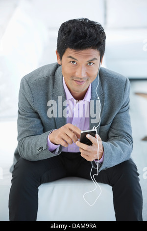 Businessman listening to headphones on sofa Stock Photo