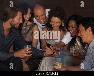 Friends using cell phone at party Stock Photo
