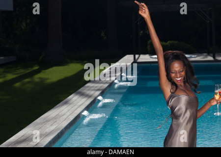 Woman dancing by swimming pool at party Stock Photo