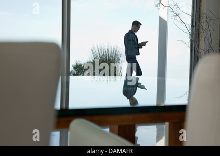 Businessman using cell phone at office window Stock Photo