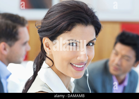 Businesswoman listening to headphones in office Stock Photo