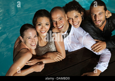 Fully dressed friends smiling in swimming pool