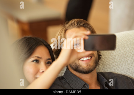Couple using cell phone as camera together on sofa Stock Photo