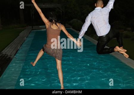 Fully dressed friends jumping into swimming pool Stock Photo