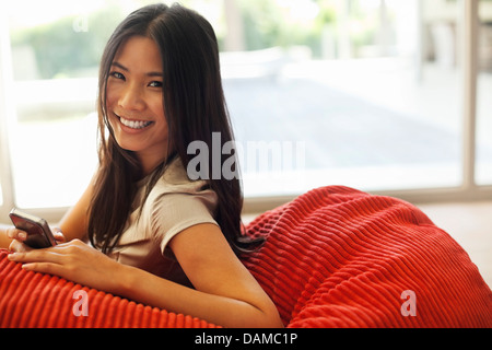 Woman using cell phone in beanbag chair Stock Photo