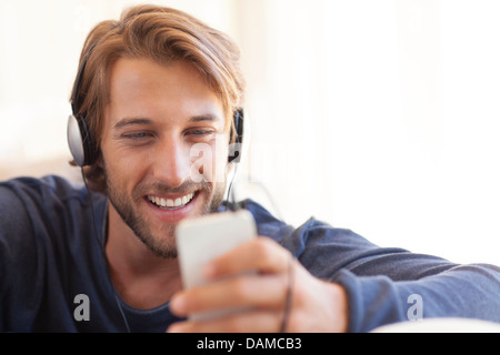 Man listening to headphones on sofa Stock Photo