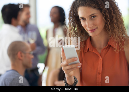 Woman using cell phone at party Stock Photo