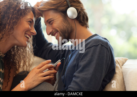 Couple listening to headphones on sofa Stock Photo