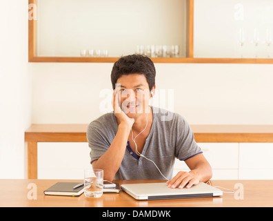 Man listening to headphones at table Stock Photo