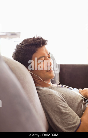 Man listening to headphones on sofa Stock Photo