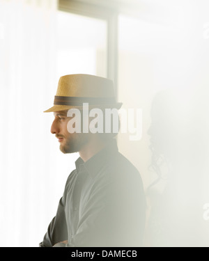 Man in straw hat looking out window Stock Photo