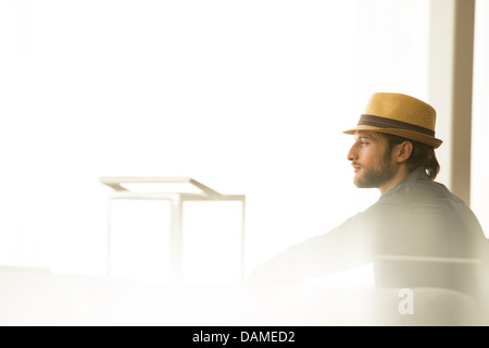 Man in straw hat looking out window Stock Photo