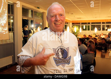 German basketball player Dirk Nowitzki's father Joerg Nowitzki points to the Dallas Mavericks logo on his shirt during live coverage of game 6 of the NBA Finals at a bar in Wuerzburg, Germany, 13 June 2011. Wuerzburg-based Dirk Nowitzki and his Dallas Mavericks won 105:95 and claimed the series 4:2. Photo: Daniel Karmann Stock Photo