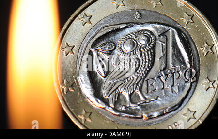 (FILE ILLUSTRATION) An archive illustration dated 24 May 2011 shows the flame from a lighter lighting up a one euro coin from Greece in Frankfurt Main, Germany. The question of how to handle Greece and the debt crisis will be discussed at the meeting of the ECB governing council on 09 June 2011 in Frankfurt Main. Photo: Boris Roessler Stock Photo